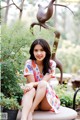 A woman sitting on a bench in a garden.