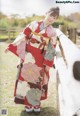 A woman in a red and white kimono standing next to a fence.