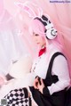 A woman with pink hair wearing bunny ears and headphones.