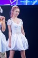 A woman in a white dress standing on a stage.