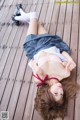 A woman laying on a wooden floor wearing a skirt and a bra.