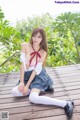 A woman in a school uniform sitting on a wooden deck.