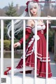 A woman in a red and white dress is posing on a railing.