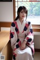 A woman in a kimono sitting on a window sill.