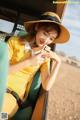 A woman in a yellow dress and hat looking at her phone.