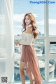 A woman standing in front of a window with a view of the city.