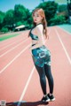 A woman standing on a running track with her hands on her hips.