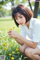 A woman kneeling down in a field of yellow flowers.