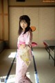 A woman in a pink kimono standing in a room.