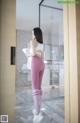 A woman in pink leggings standing in front of a mirror.