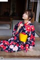 A woman in a kimono sitting on a wooden floor.