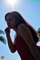 A woman in a red dress standing in front of a palm tree.