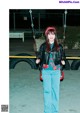 A woman standing on a swing in a parking lot.