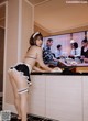 A woman in a maid outfit standing in front of a television.