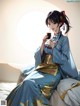 A woman in a blue kimono sitting on a bed holding a cup of coffee.