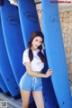 A woman standing next to a row of blue surfboards.