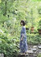 A woman standing in the middle of a lush green forest.