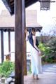 A woman in a blue and white dress standing on a wooden deck.